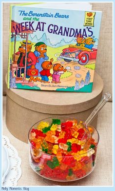 a bowl filled with gummy bears next to a book