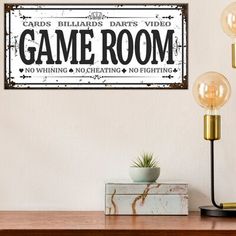 a wooden sign that says game room on the side of a wall above a table