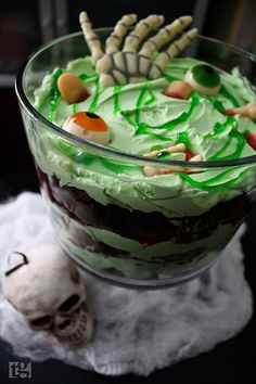 a halloween trifle with green frosting and sprinkles in a glass bowl