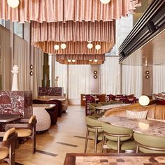 the interior of a restaurant with tables, chairs and chandeliers hanging from the ceiling