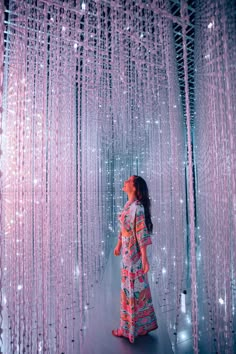 a woman standing in front of a wall covered with beads