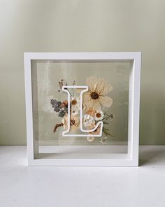 the letter j is surrounded by flowers in a white frame on top of a table