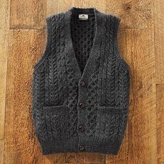 a gray sweater vest sitting on top of a wooden floor