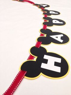 mickey mouse name banner with red ribbon on white sheeted bedding, ready to be made into a birthday decoration