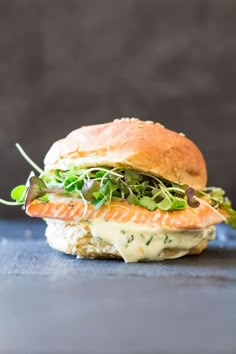 a sandwich with salmon, lettuce and sauce on it sitting on a table