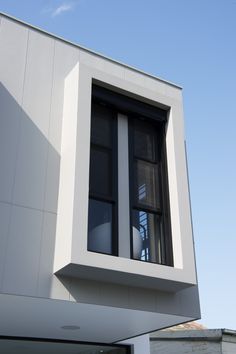 a white building with two windows on the top floor and one window in the middle