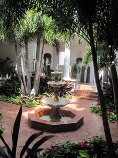 a fountain in the middle of a courtyard surrounded by trees