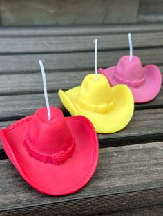 three different colored cowboy hats sitting on top of a wooden bench next to each other