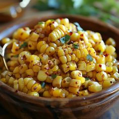 a wooden bowl filled with corn and garnished with parsley on the side