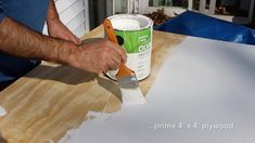 a man is painting the outside of a house with white paint and a green brush