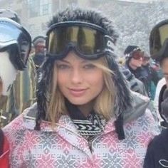 two women standing next to each other with ski goggles on their heads and one woman wearing snow gear