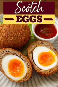 scotch eggs on a paper plate with ketchup and dipping sauce in the background