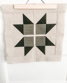 a piece of fabric hanging on a wall with two black and white squares in the middle