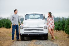 a man and woman standing next to an old truck