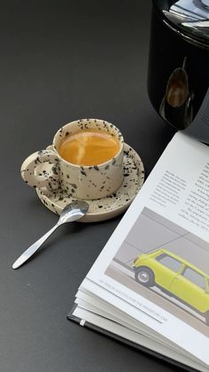 a cup of coffee sitting on top of a saucer next to an open book