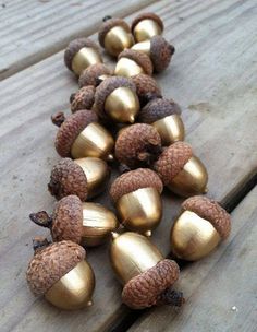 some gold acorns are laying on a wooden table with pine cones in the middle