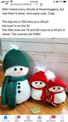 two knitted snowmen sitting next to each other on top of a wooden floor