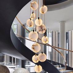 an elegant chandelier hanging from a spiral staircase in a modern home with marble balls