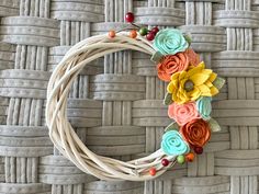 a close up of a wreath made out of yarn and flowers on a woven surface