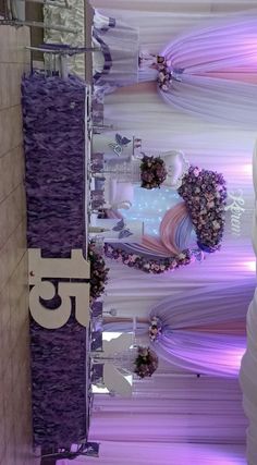 the ceiling is decorated with purple and white ribbons, flower arrangements, and flowers in vases