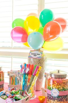 a candy bar with balloons and confetti on the table