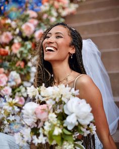 a woman sitting on the steps with flowers in front of her smiling and holding a bouquet