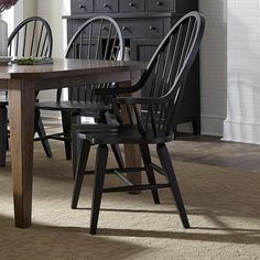 a dining room table with four chairs and a vase on top of it in front of a dresser