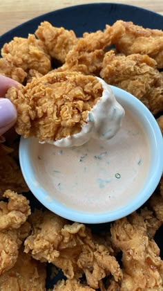 a person dipping some kind of sauce on fried chicken patties with ranch dressing in a blue bowl