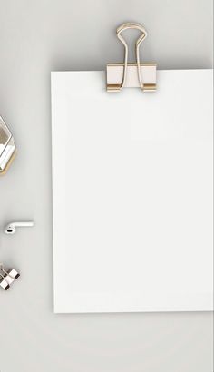 an office desk with a clipboard, pen and paper clips on top of it