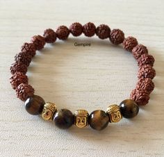 "Rudraksha and Tiger Eye Bracelet in Elastic This is a bracelet for Protection, Action, Empowerment, and Emotional Balance --> Bead size - 8 mm approximately --> Stretchable in elastic Visit our shop here- https://etsy.me/2IgCTfg Rudraksha are traditionally used as prayer beads. They are associated with Lord Shiva and the name Rudraksha translates to the Shiva's tears. They commonly worn by his devotees. They are worn as a form of protection as they are said to provide a kind of protective energ Rudraksha Bracelet, Tigers Eye Bracelet, Sandalwood Mala, Buddha Bracelets, Wood Bead Necklace, Tiger Eye Bracelet, Yoga Bracelet, Tiger Eye Beads, Emotional Balance