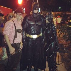 two men dressed up as batman and catwoman pose for a photo on the sidewalk