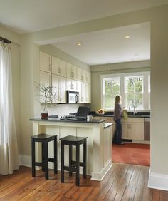 a woman standing in a kitchen next to two stools