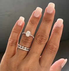 a woman's hand with two wedding rings on her left and the other hand holding an engagement ring