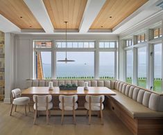 a long table with chairs and benches in front of large windows