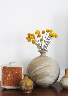 vases with yellow flowers in them sitting on a wooden table next to other objects