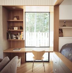 a bedroom with a bed, desk and bookcases in front of a window