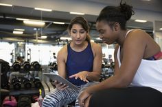 two women in a gym looking at something on a tablet