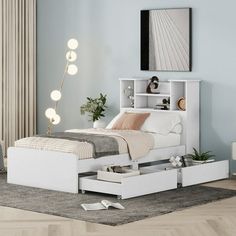 a white bed with drawers underneath it in a room