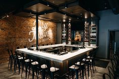 an empty bar with lots of stools and bottles on the wall next to it