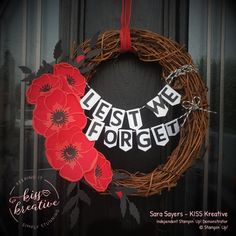 a wreath with red flowers on it and the words west we forgett written in white