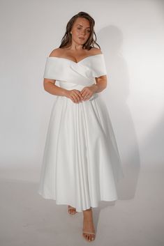 a woman in a white dress posing for the camera with her hands on her hips