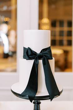 a white and black wedding cake with a bow on top