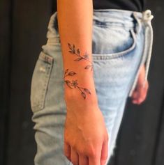 a woman's arm with a small flower tattoo on the left side of her wrist