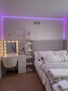 a bedroom with a bed, desk and lights on the wall above it's headboard