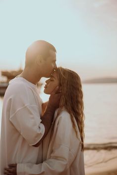 a man and woman standing next to each other near the water