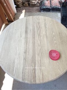 a wooden table with a red plastic object on it's surface in front of a pile of wood