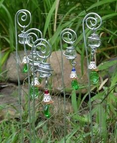 three metal wind chimes sitting on top of a lush green field next to a rock