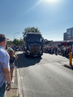 a large truck driving down a street next to a crowd