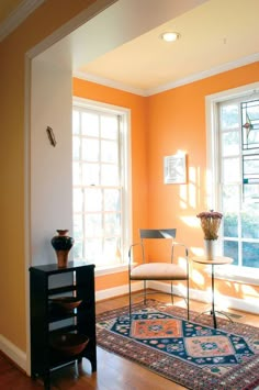 a living room with orange walls and hardwood floors, furniture and rugs on the floor