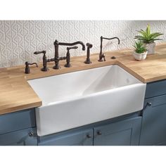 a white sink sitting on top of a wooden counter next to a potted plant